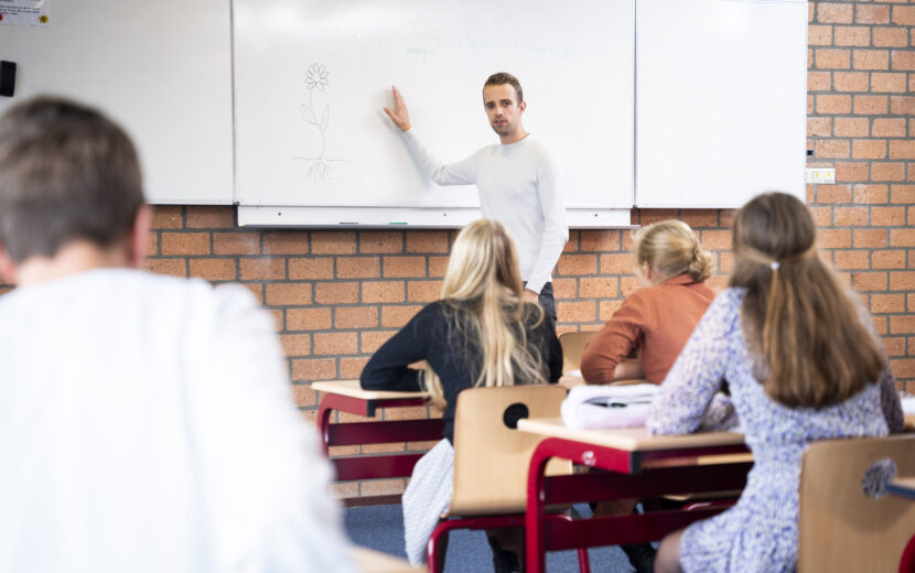 Docent geeft uitleg in klaslokaal.